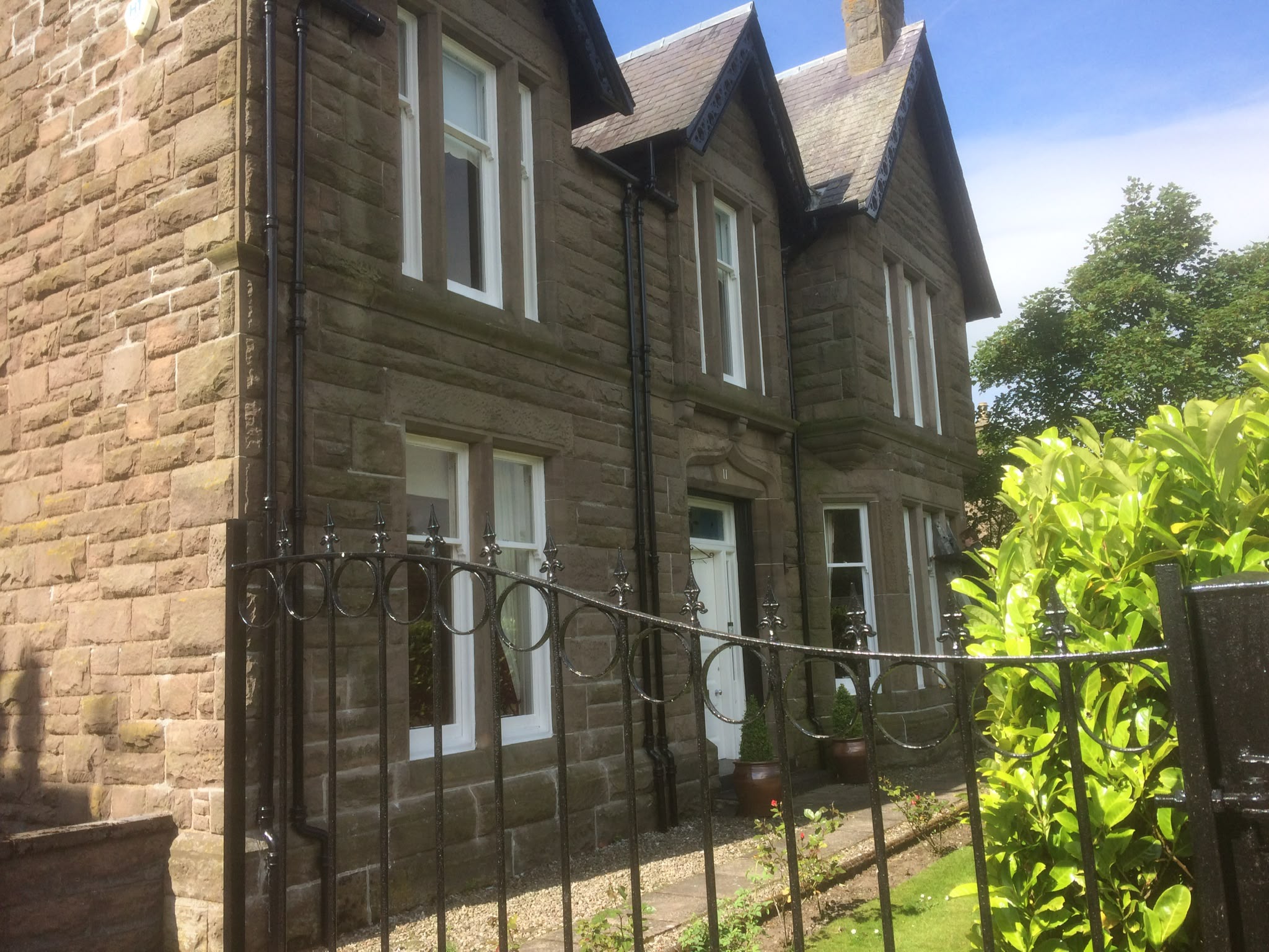 Sandstone house with white-painted sash windows, a painted door and black railings.